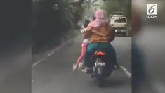 Emak-emak ini membonceng anaknya dengan cara digendong dari samping, sehingga si anak bergelantungan.