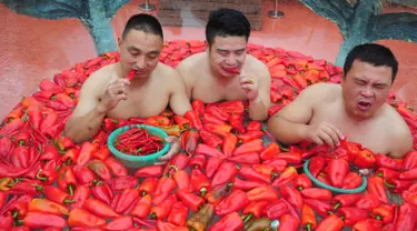 Para peserta memakan cabai sambil berendam dalam gentong berisi air dan ratusan cabai di Ningxiang, Provinsi Hunan, Tiongkok, 12 Agustus 2017. Kompetisi makan cabai ini digelar untuk mendongkrak popularitas pariwisata di Provinsi Hunan. (STR / AFP)