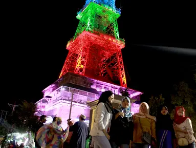 Warga berfoto dekat Pakaya Tower di kawasan taman Limboto, Kabupaten Gorontalo, Sabtu (12/1). Pakaya Tower berdiri megah bak Menara Eiffel dengan tata lampu warna-warni. (Liputan6.com/Arfandi Ibrahim)