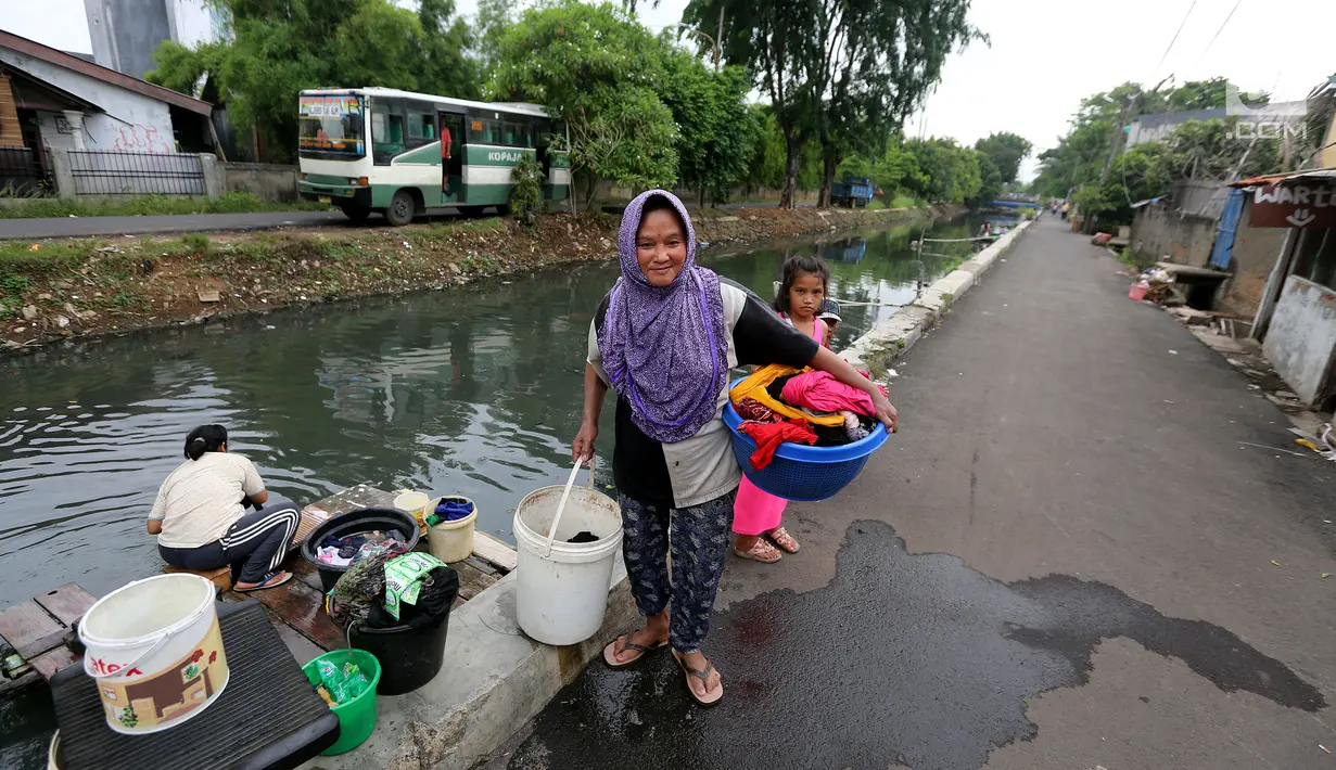 Seorang wanita membawa pakaiannya usai di cuci di aliran Kali Maja, Jakarta, Selasa (7/11). Air Kali Maja yang yang kotor dan tidak layak, terpaksa dimanfaatkan untuk memenuhi kebutuhannya terutama mencuci pakaian. (Liputan6.com/JohanTallo)