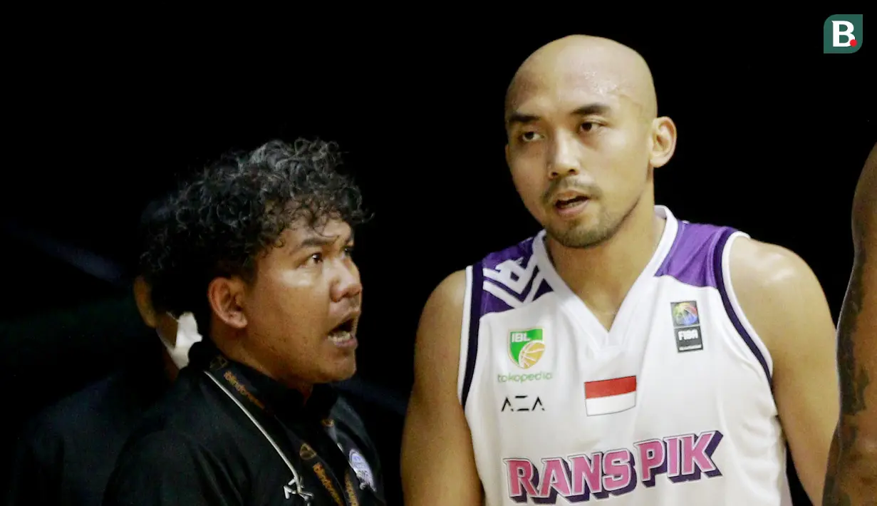 Pelatih Rans PIK Basketball, Koko Heru Setyo Nugroho (kiri) memberikan instruksi kepada Bima Riski Ardiansyah saat melawan Satria Muda Pertamina pada laga IBL 2022 di Hall Basket GBK, Jakarta, Rabu (19/01/2022). Satria Muda menang dengan skor 64-32. (Bola.com/M Iqbal Ichsan)