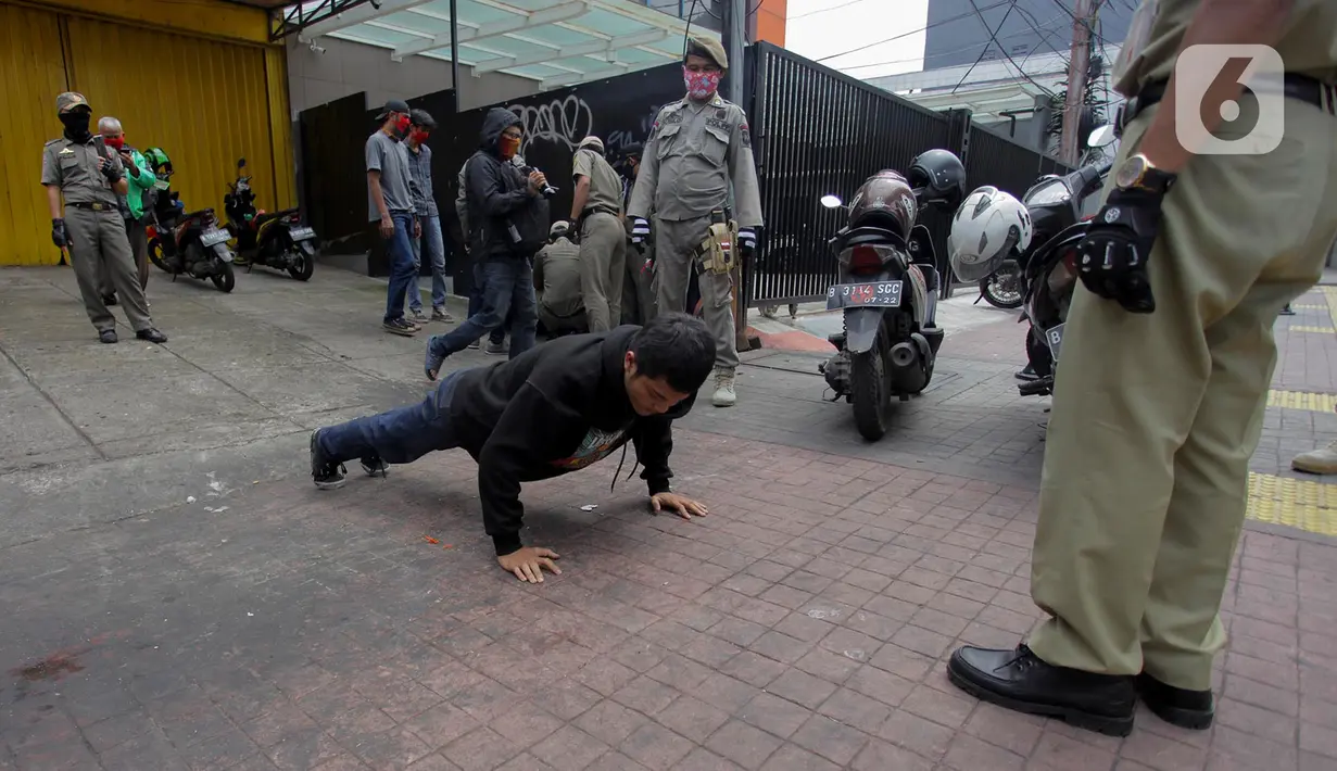 Petugas gabungan memberikan hukuman push up kepada warga yang tidak memakai masker saat razia Pembatasan Sosial Berskala Besar (PSBB) di Kawasan Jalan Fatmawati, Jakarta, Selasa (28/4/2020). Penertiban terkait pelaksanaan PSBB Jakarta dan memutus rantai penyebaran COVID 19. (merdeka.com/Imam Buhori)