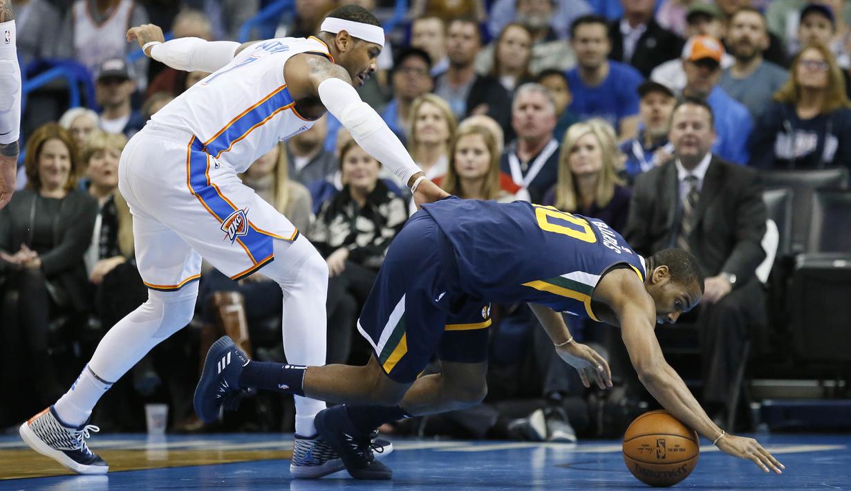 Pebasket Utah Jazz, Alec Burks, terjatuh saat berebut bola dengan pebasket Oklahoma City Thunder, Carmelo Anthony, pada laga NBA di Chesapeake Energy Arena, Rabu (6/12/2017). Thunder menang 100-94 atas Jazz. (AP/Sue Ogrocki)