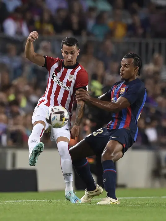 Pemain depan Athletic Bilbao Alex Berenguer berebut bola dengan bek Barcelona Jules Kounde (kanan) pada pekan ke-11 Liga Spanyol 2022/2023 di Camp Nou, Senin dini hari WIB (24/10/2022). Berkat kemenangan ini, Barcelona masih tetap mampu menjaga jarak dengan pemuncak klasemen Real Madrid. (Photo by Josep LAGO / AFP)