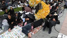 Warga mengenakan pakaian hitam menunggu pemakaman mendiang Raja Thailand Bhumibol Adulyadej di Bangkok (25/10). Prosesi kremasi penguasa monarki terlama Thailand itu baru akan dilakukan pada hari Kamis (26/10/2017). (AFP Photo/Roberto Schmidt)