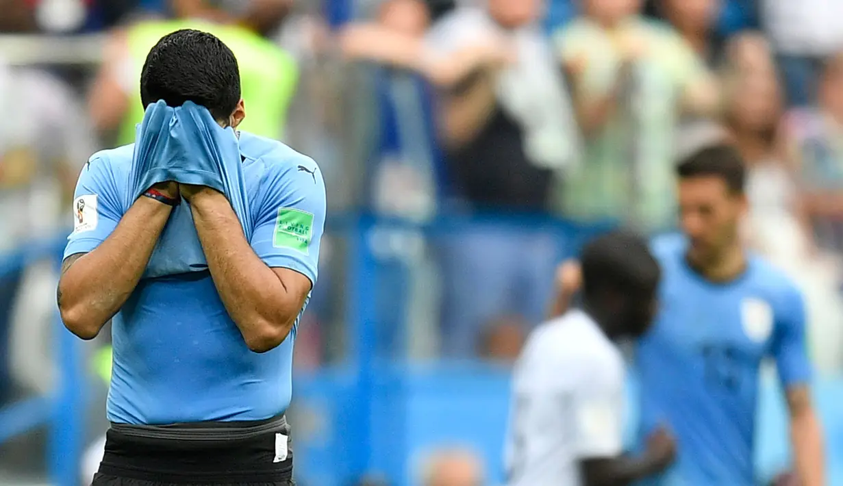 Striker Uruguay, Luis Suarez bersedih sambil menutupi wajah dengan jersey setelah kalah atas Prancis pada perempat final Piala Dunia 2018 di Nizhny Novgorod Stadium, Jumat (6/7). Timnas Uruguay tersingkir usai ditumbangkan Prancis 0-2 . (AP/Hassan Ammar)