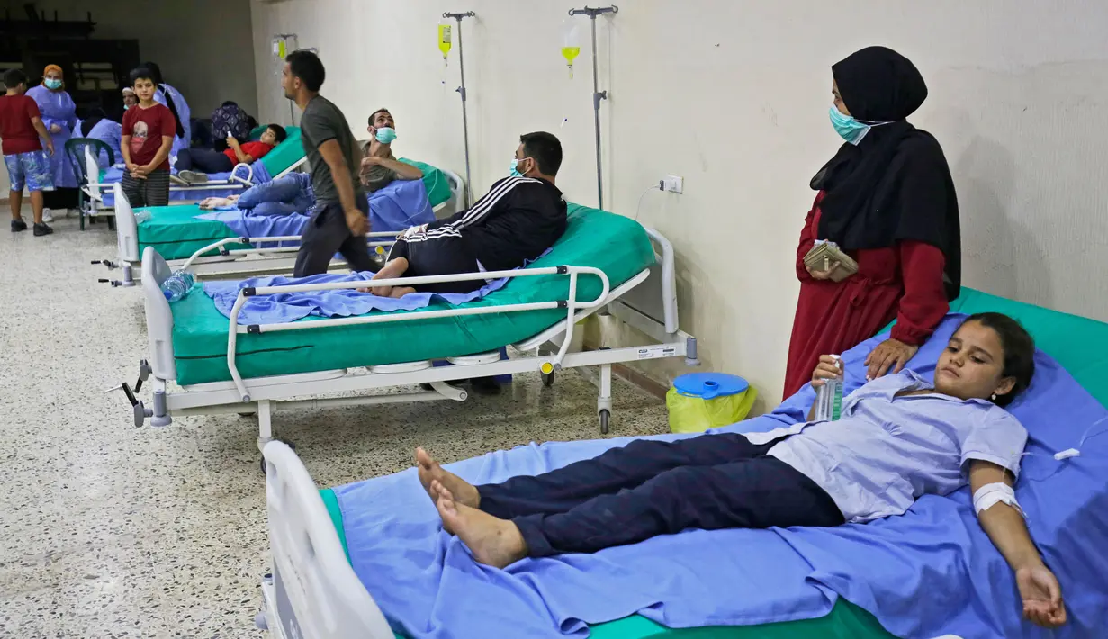 Pasien yang terinfeksi wabah kolera Vibrio menerima perawatan di aula masjid yang diubah menjadi rumah sakit lapangan di Kota Bebnine, Distrik Akkar, Lebanon Utara, Rabu (26/10/2022). Kolera adalah infeksi enterik akut yang disebabkan oleh bakteri Vibrio cholerae yang ada dalam air atau makanan yang terkontaminasi. (AFP/Ibrahim Chalhoub)