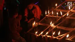 Anak-anak menyalakan lampu minyak saat perayaan tumbilotohe atau penyalaan berjuta lampu minyak di akhir Ramadan di Kota Gorontalo, Jumat (31/5/2019). Ribuan warga tumpah ruah ke sejumlah tempat untuk menyaksikan indahnya hiasan lampu temaram tersebut. (Liputan6.com/Arfandi Ibrahim)