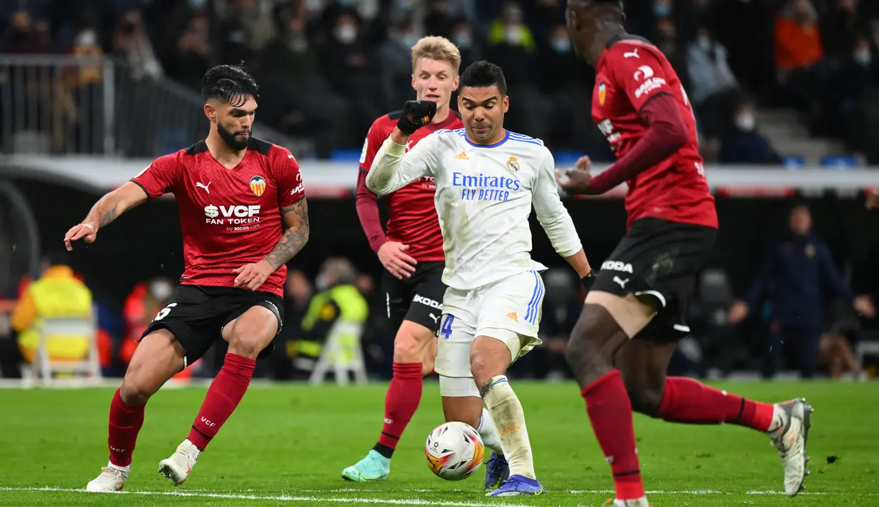 Bek Valencia Omar Alderete (kiri) menantang gelandang Real Madrid Casemiro (kedua kanan) pada laga pekan ke-20 La Liga Spanyol di Santiago Bernabeu Valencia, Minggu dini hari WIB (9/1/2022). Real Madrid menang meyakinkan 4-1 atas Valencia. (GABRIEL BOUYS / AFP)