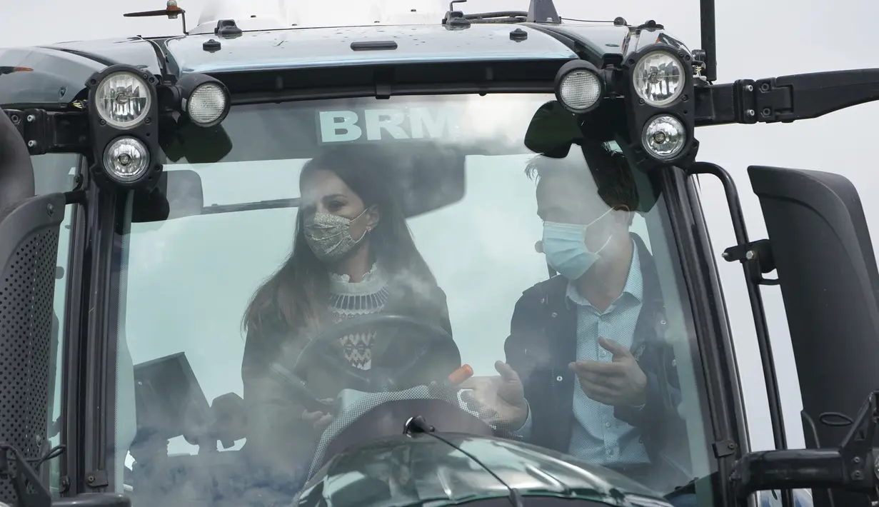 Duchess of Cambridge Kate Middleton mendapat pengarahan bagaimana mengemudikan traktor dari petani Stewart Chapman saat kunjungan dengan Pangeran William ke Manor Farm di Little Stainton, Durham, Inggris, Selasa (27/4/2021). (Owen Humphreys/Pool via AP)