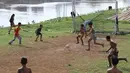 Anak-anak bermain sepak bola di bantaran Kanal Banjir Barat, Jakarta, Jumat (5/4). Tidak adanya lapangan menjadikan lokasi tersebut sebagai tempat bermain mereka, meskipun dalam kondisi seadanya. (Liputan6.com/Immanuel Antonius)