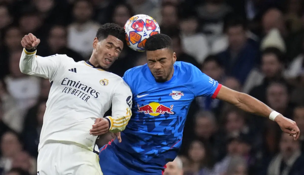 Pemain Real Madrid, Jude Bellingham (kiri) berduel udara dengan pemain RB Leipzig, Benjamin Henrichs pada laga leg kedua 16 besar Liga Champions 2023/2024 di Santiago Bernabeu, Madrid, Spanyol, Kamis (07/03/2024) WIB. (AP Photo/Manu Fernandez)