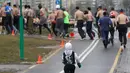 Seorang anak ikut berlari dalam acara "Real men's race" di Minsk, Belarusia, Kamis (23/2). Ratusan pria bertelanjang dada sambil berlari keliling Kota Minsk untuk memperingati Hari Pertahanan Tanah Air. (AP Photo/Sergei Grits)