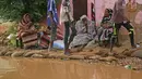 Penduduk Sudan duduk di luar rumah mereka yang banjir di daerah alqamayir di kota kembar ibu kota Omdurman (26/8/2020). (AFP Photo/Ashraf Shazly)