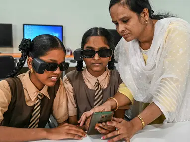 Seorang instruktur membantu para siswa disabilitas netra dalam menggunakan kacamata pintar berteknologi Artificial Intelligence (AI) di sebuah sekolah tunanetra di Hyderabad, India pada Jumat 22 November 2024. (NOAH SEELAM/AFP)