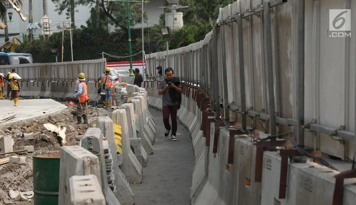 Pejalan kaki melintasi proyek revitalisasi trotoar di kawasan Bundaran Hotel Indonesia, Jakarta, Selasa (24/9/2019). Pemerintah Provinsi (Pemprov) DKI tengah mengebut pembangunan revitalisasi trotoar di sejumlah titik Ibu Kota yang ditargetkan rampung akhir 2019 mendatang (Liputan6.com/Angga Yuniar)