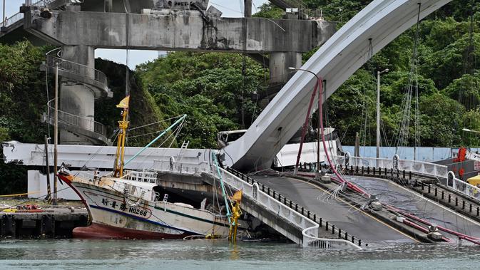 Sebuah kapal nelayan tertimpa jembatan beton yang ambruk di pelabuhan ikan Nanfangao di kota Suao (1/10/2019). Kejadian tersebut membuat setidaknya 14 orang terluka. (AFP Photo/Sam Yeh)