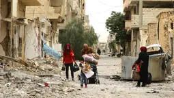 Sebuah keluarga melewati reruntuhan bangunan untuk kembali ke rumah mereka di kota modern Palmyra, berdekatan dengan kota kuno Suriah, Sabtu (9/4). Warga kembali ke rumah mereka setelah dibebaskannya dua kota tersebut dari tangan ISIS. (Louai BESHARA/AFP)