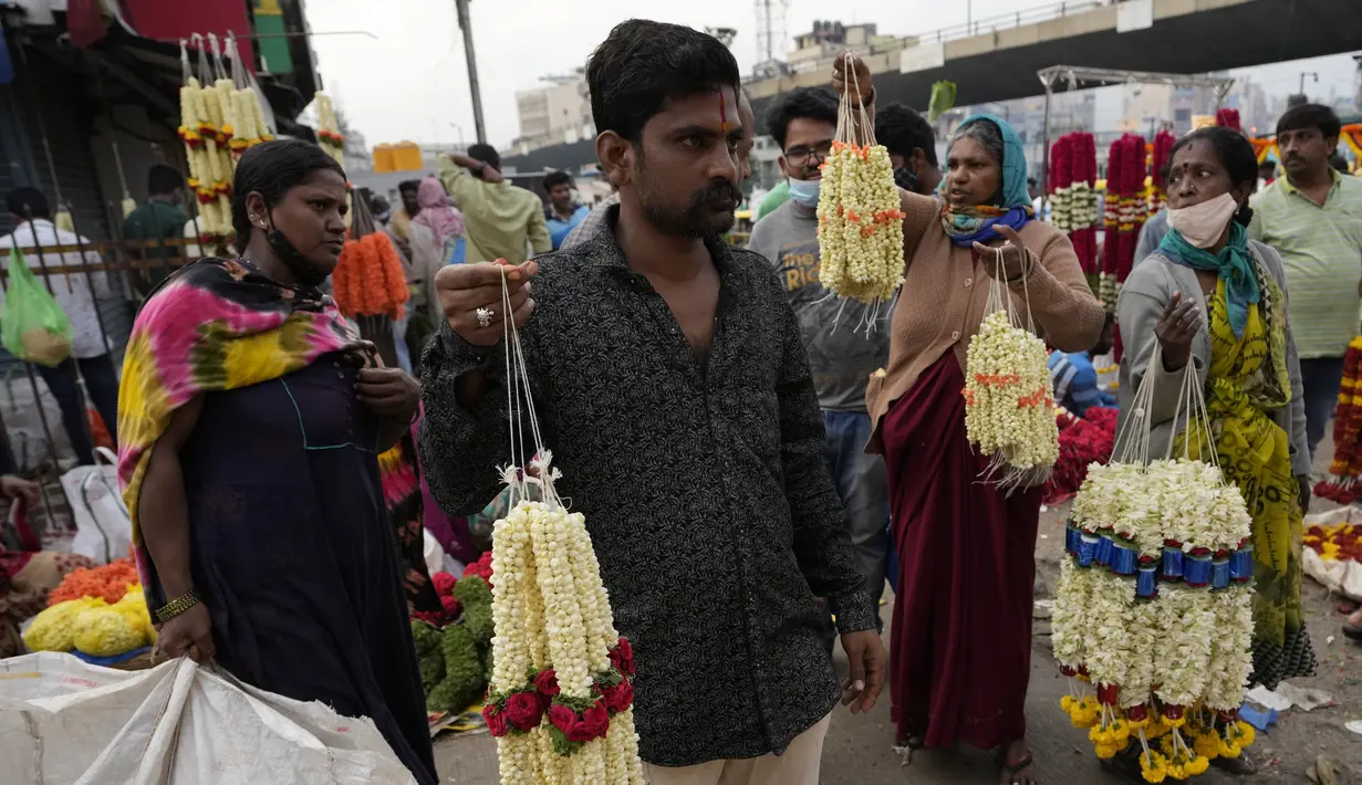 Penjual bunga menggelar karangan bunga untuk dijual di pasar grosir di Bengaluru, India, Rabu (13/4/2022). Orang-orang telah kembali beraktivitas normal setelah pihak berwenang mencabut pembatasan COVID-19 termasuk mengenakan masker wajah di tempat-tempat umum. (AP Photo/Aijaz Rahi)