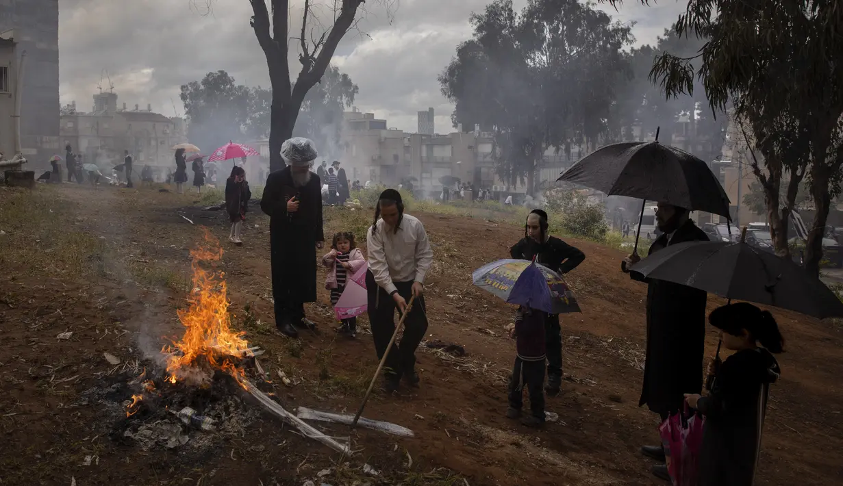 Pria dan anak-anak Yahudi Ultra-Ortodoks membakar beragi sebagai persiapan liburan Paskah di kota Yahudi ultra-Ortodoks Bnei Brak, Tel Aviv, Israel (26/3/2021).  Dalam Kitab Suci diceritakan, kaum Yahudi tidak sempat membuat roti beragi saat akan berangkat menuju tanah yang dijanjikan. (AP Photo/Ode