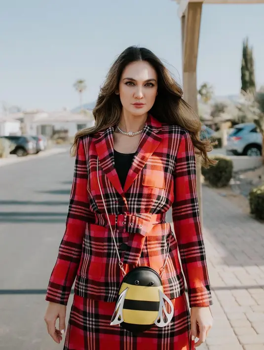 Penampilan luar biasa lainnya dari Luna Maya. Ia mengenakan oversized blazer bermotif garis kotak bernuansa merah, dipasangkan dengan midi skirt dengan slit yang serasi, dan high boots hitam. [Foto: Instagram/lunamaya]
