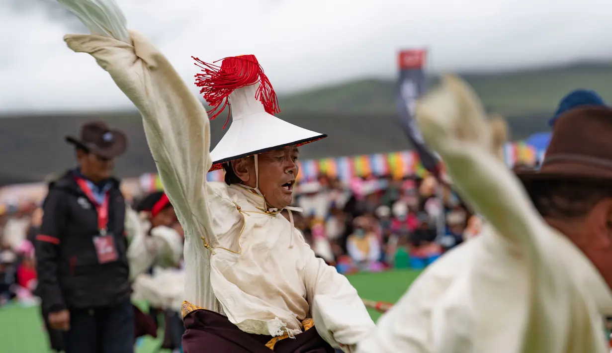 Seorang penggembala menyemangati rekan timnya dalam kompetisi tarik tambang di Wilayah Damxung, Daerah Otonom Tibet, China, 10 Agustus 2020. Dengan pakaian tradisional, para penggembala dari sejumlah desa di Wilayah Damxung berpartisipasi dalam permainan tradisional itu. (Xinhua/Purbu Zhaxi)