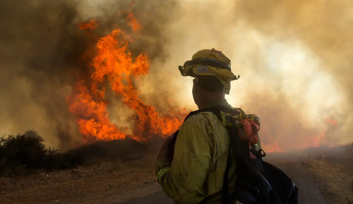 Petugas melihat kebakaran hutan di Cherry Valley, California (1/8/2020). Hampir setiap tahun, California dilanda kebakaran besar-besaran yang menyebabkan polusi udara tinggi. (AP Photo/Ringo H.W. Chiu)