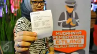 Seorang wanita menunjukkan bukti pembayaran denda tilang dengan tilang online atau e-tilang melalui mesin ATM BRI di Jakarta, Jumat (16/12). Pembayaran elektronik ini sekaligus diklaim bisa menghilangkan praktik percaloan. (Liputan6.com/Angga Yuniar)