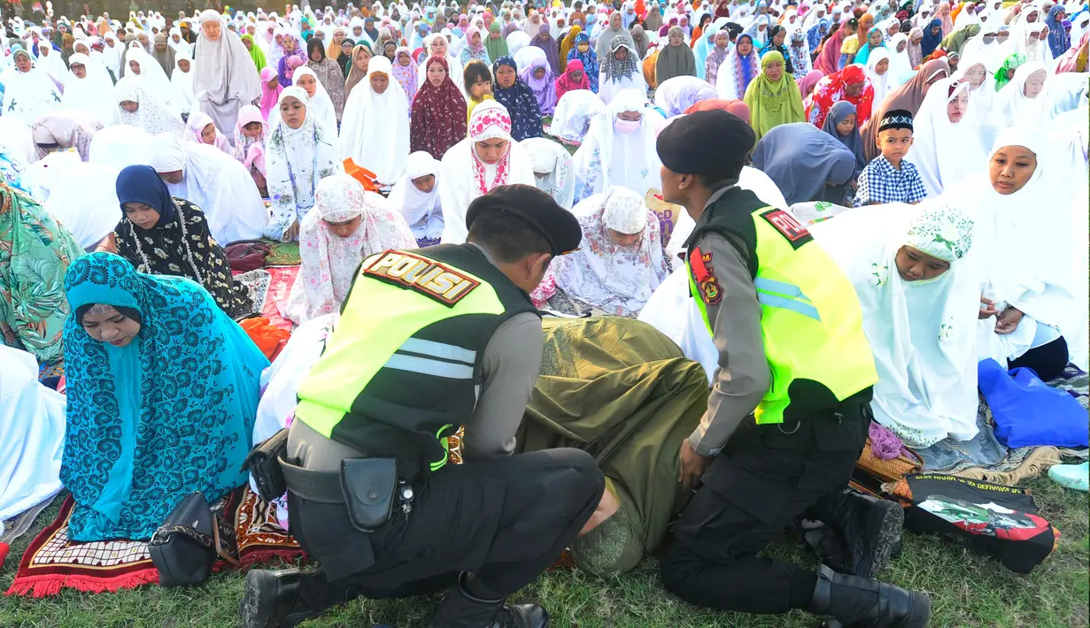 Jemaah perempuan yang pingsan langsung dievakuasi dua petugas polisi. (merdeka.com/Arie Basuki)