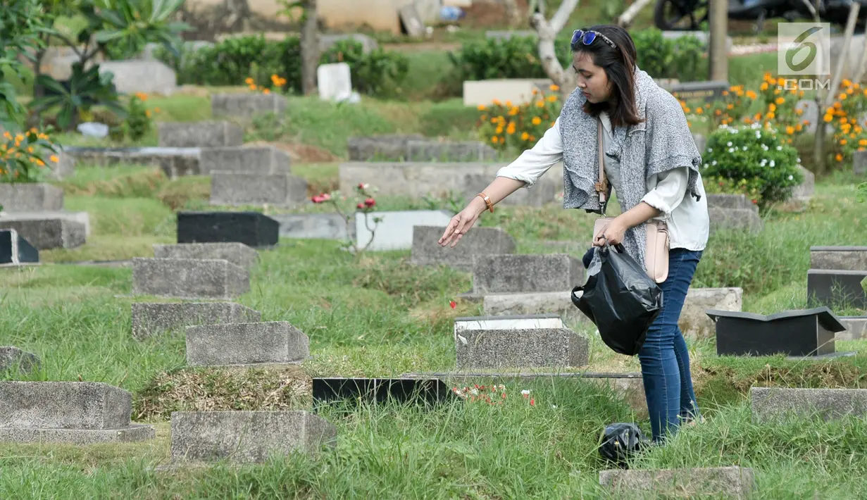 Seorang wanita menabur bunga pada makam keluarga di Tempat Pemakaman Umum (TPU) Karet Bivak, Jakarta, Minggu (25/6). Tradisi ziarah yang dilakukan orang muslim setelah melakukan salat Idul Fitri adalah acara tahunan. (Liputan6.com/Yoppy Renato)