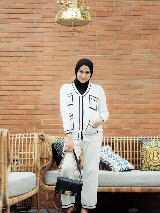 Nina Zatulini tampil elegan memadukan blus panjang bermotif dan celana kulot putih. @ninazatulini22.