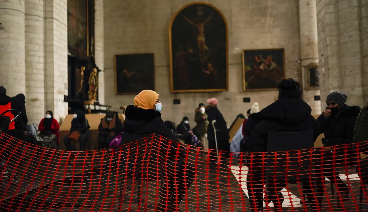 Para perempuan, mengenakan masker, mengobrol saat mereka menempati gereja Saint-Jean-Baptiste-au-Beguinage di Brussels, Belgia, Selasa (2/2/2021). Para imigran tanpa surat-surat resmi telah menduduki gereja untuk menarik perhatian otoritas Brussel atas penderitaan mereka. (AP Photo/Francisco Seco)