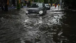 Sejumlah mobil melewati jalan yang tergenang air di tengah hujan lebat di Kolkata (20/9/2021). Hujan dilaporkan dipicu oleh sirkulasi siklon yang terbentuk di atas Teluk Benggala. (AFP/Dibyangshu Sarkar)