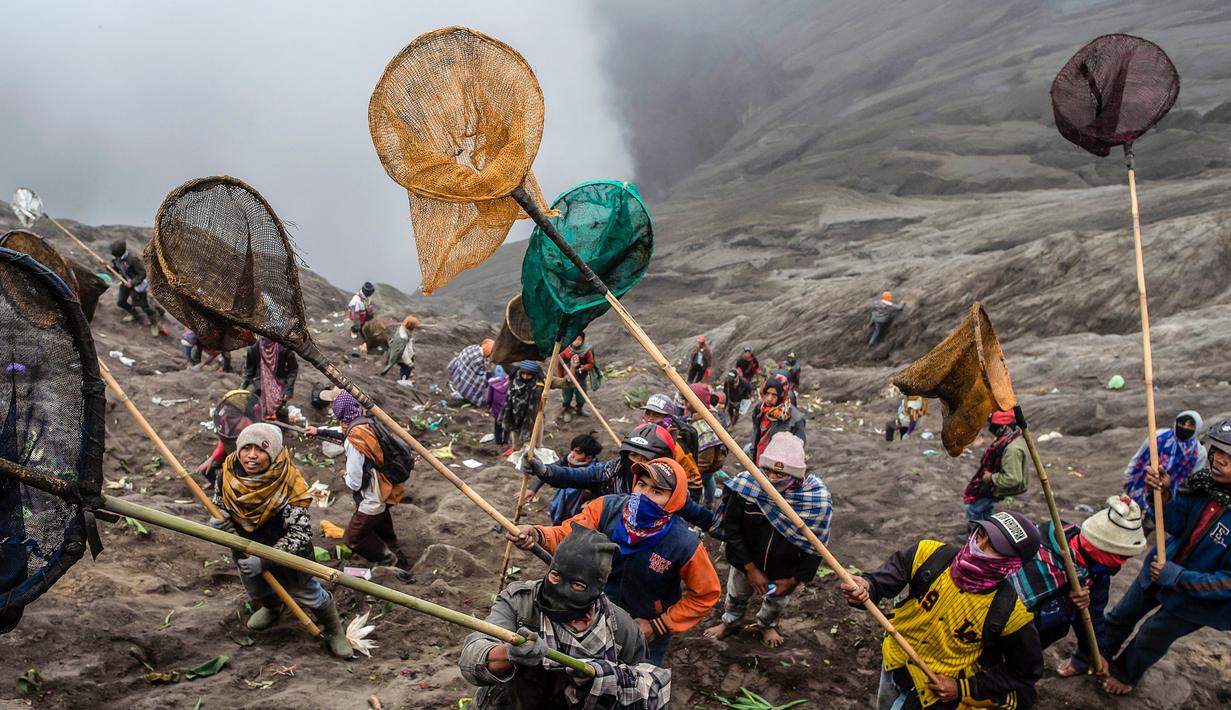 Sejumlah orang mencoba menangkap sajen yang dilemparkan ke kawah dalam ritual Yadnya Kasada di Gunung Bromo, Probolinggo, Jawa Timur, Kamis (18/7/2019). Ritual ini diselenggarakan berabad-abad silam saat manusia pertama kali mendiami kawasan kaki Gunung Bromo. (JUNI KRISWANTO/AFP)