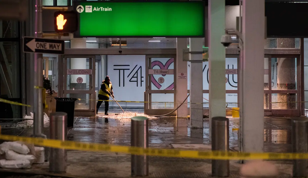 Petugas membersihkan air yang membanjiri Bandara Internasional John F Kennedy (JFK), New York, Senin (8/1). Air mengalir hingga menggenangi Terminal 4 dan anjungan bagasi Bandara JFK, juga membasahi sebagian besar koper penumpang. (Jewel SAMAD / AFP)