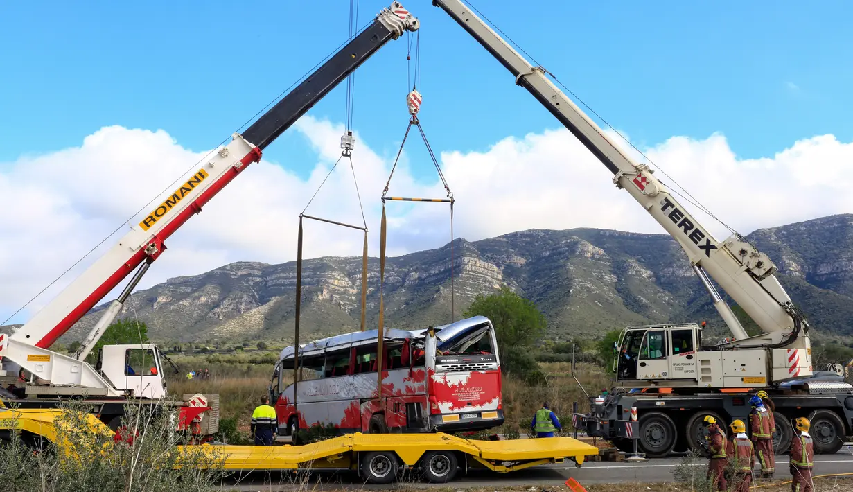 Dua crane dikerahkan untuk mengevakuasi sebuah bus di Jalan Raya AP7 dekat Kota Freginals, Spanyol, Minggu (20/3). Bus berisi 57 penumpang yang mayoritas mahasiswa asing itu terbalik ketika dalam perjalanan dari Valencia menuju Barcelona (PAU Barrena/AFP)