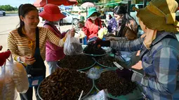 Orang-orang membeli tarantula goreng di kota Skun di provinsi Kampong Cham pada 15 Januari 2023. Wisatawan yang mengunjungi Kamboja sering kali menjadikan tarantula sebagai cemilan yang menantang adrenalin mereka. (Photo by TANG CHHIN SOTHY / AFP)