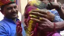 Sejumlah pria mengolesi bubuk warna pada wajah seorang gadis saat merayakan festival Holi di sebuah kuil di desa Nandgaon, Uttar Pradesh, 5 Maret 2020. Festival Holi diselenggarakan pada awal musim semi yaitu pada akhir Februari hingga Maret, tepatnya sesudah bulan purnama. (Money SHARMA/AFP)