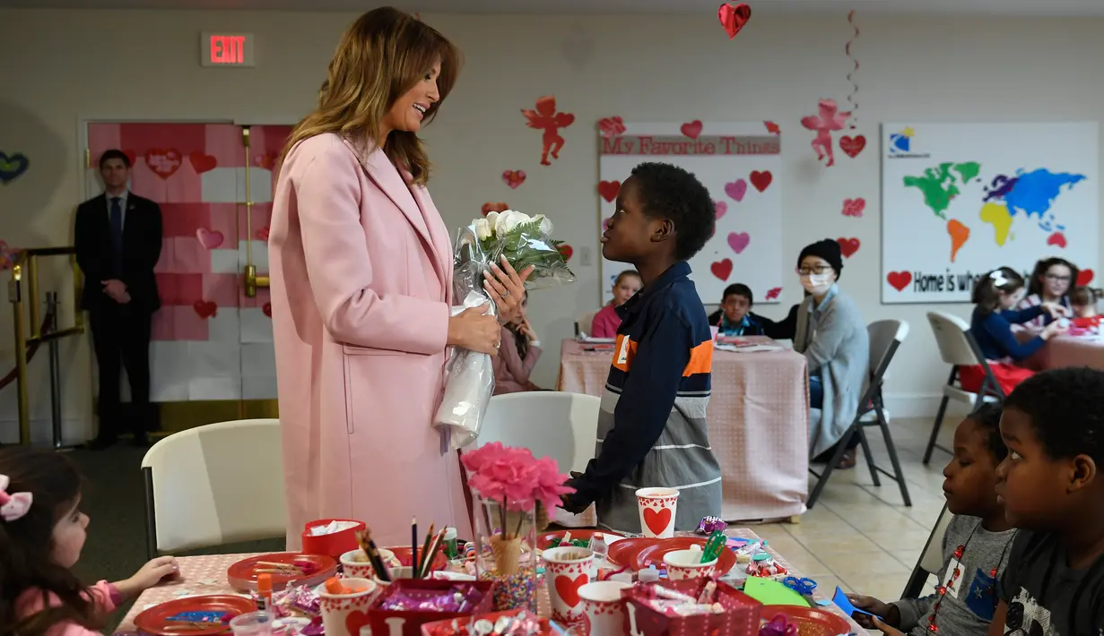 Melania Trump menerima buket bunga dari Amani (13) asal Kenya dalam kunjungannya di rumah sakit National Institutes of Health, Maryland, Kamis (14/2). Melania Trump menghabiskan momen Hari Valentine bersama anak-anak di rumah sakit.  (AP/Susan Walsh)