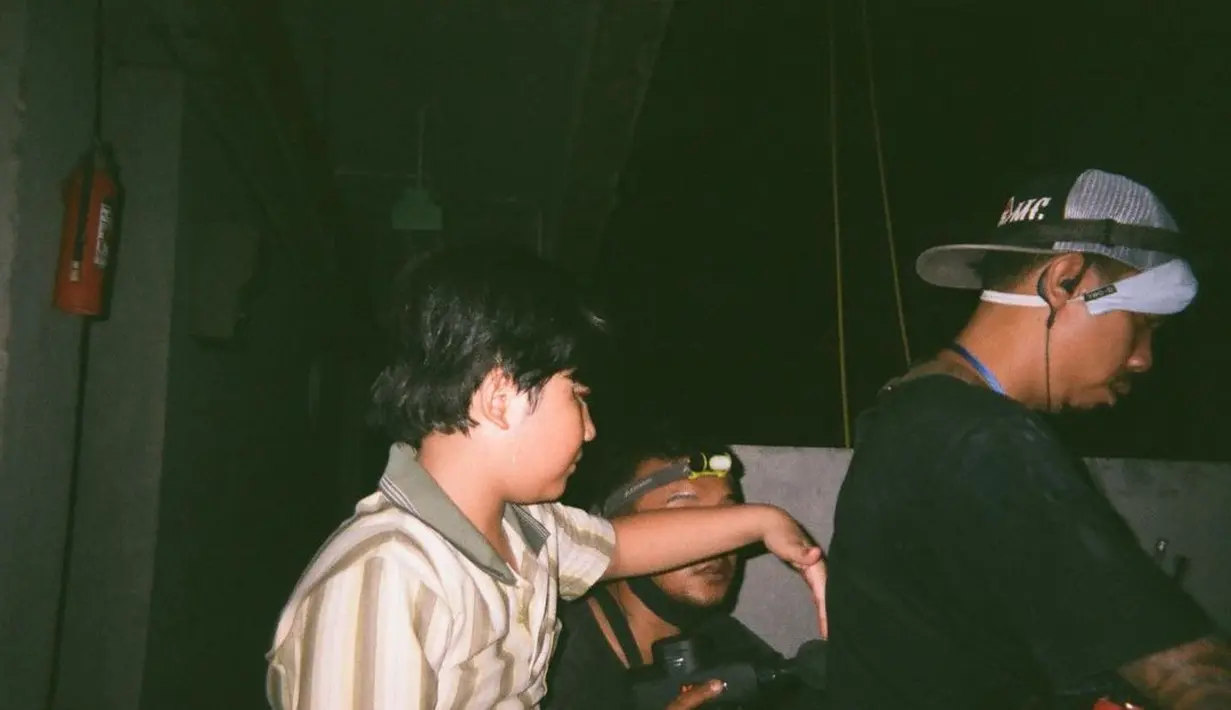 Tokoh baru lainnya adalah Wisnu, bocah bernasib malang tetangga Rini (Tara Basro). Wisnu diperankan Muzzaki Ramdhan, yang sebelumnya dikenal lewat film laris Gundala. Dalam foto, Muzzaki yang pakai kemeja lengan pendek motif garis turangga sedang berinteraksi dengan kru di sela syuting. Perannya dalam Pengabdi Setan 2 cukup krusial. (Foto: Dok. Instagram @endyarfian22)