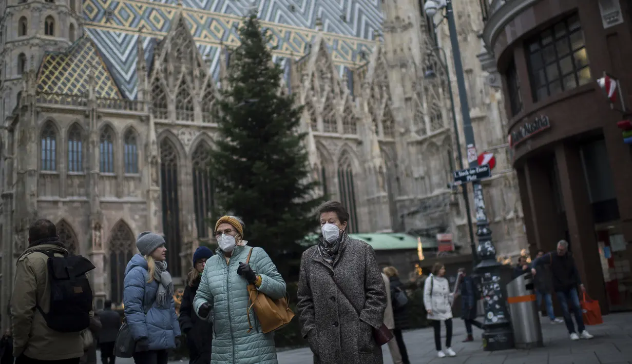 Orang-orang yang memakai masker wajah untuk melindungi diri dari virus corona saat mereka berjalan di depan Katedral St. Stephen di Wina, Austria, Rabu (17/11/2021). Mereka yang tidak divaksinasi Covid-19 dan melanggar penguncian terancam denda hingga 1.450 euro. (AP Photo/Michael Gruber)