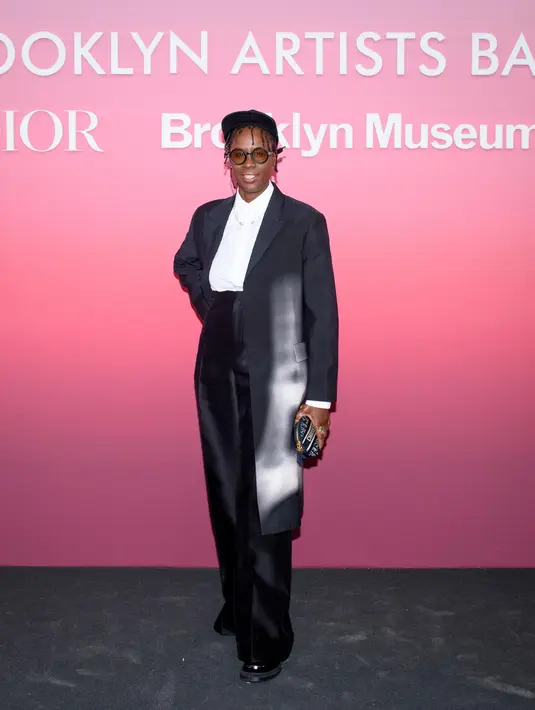 Mickalene Thomas mengenakan mantel bermotif hitam Dior Spring-Summer, kemeja katun putih, dan celana wol hitam. Dia juga memakai sepatu Dior. [Dior]