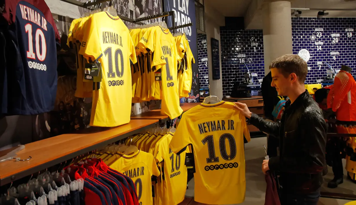 Suporter PSG melihat jersey penyerang Neymar Jr di toko Paris Saint Germain di Paris (4/8). PSG resmi membeli Neymar dari Barcelona setelah menebus klausul pelepasan kontrak senilai 222 juta Euro, atau sekitar Rp 3,5 triliun. (AP Photo/Michel Euler)