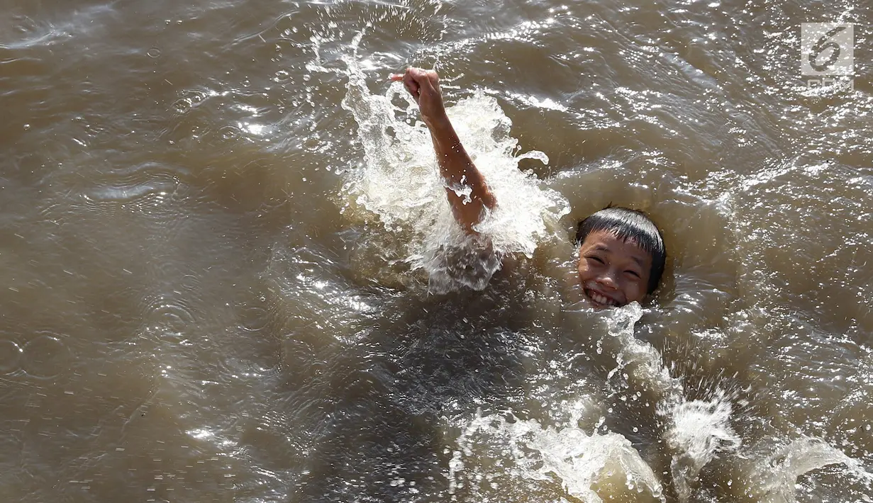 Seorang anak berenang di Kanal Banjir Barat, Jakarta, Jumat (23/3). Mahalnya biaya sewa kolam renang menyebabkan anak-anak berenang tidak pada tempatnya. (Liputan6.com/Immanuel Antonius)