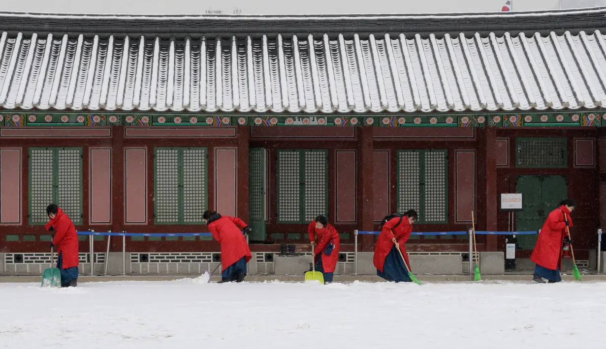 Sejumlah wanita mengenakan pakaian tradisional Korea "Hanbok" membersihkan salju di Istana Gyeongbok di Seoul, Korea Selatan (15/2). Istana Gyeongbok aslinya didirikan tahun 1394 oleh Jeong do jeon, seorang arsitek.  (AP Photo/Ahn Young-joon)
