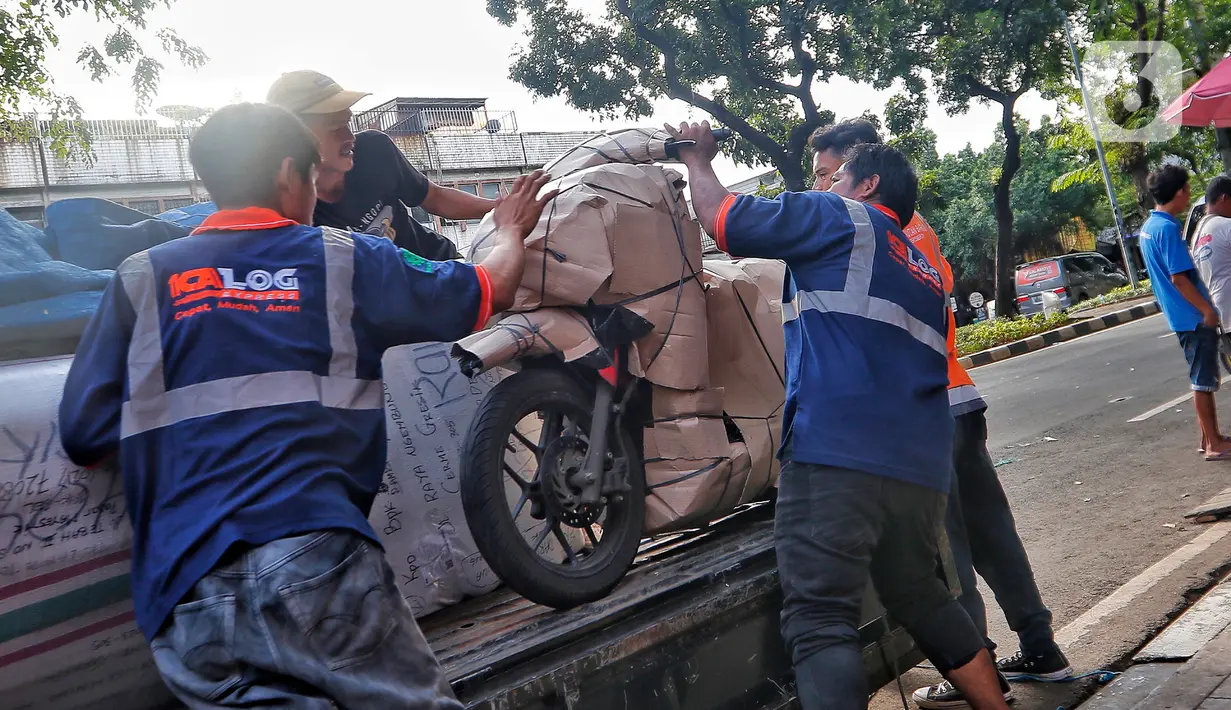 Pekerja tengah mengepak sepeda motor yang akan dikirim melalui jasa pengiriman dengan kereta api di Kawasan Stasiun Senen, Jakarta, Kamis (13/4/2023).(Liputan6.com/Angga Yuniar)