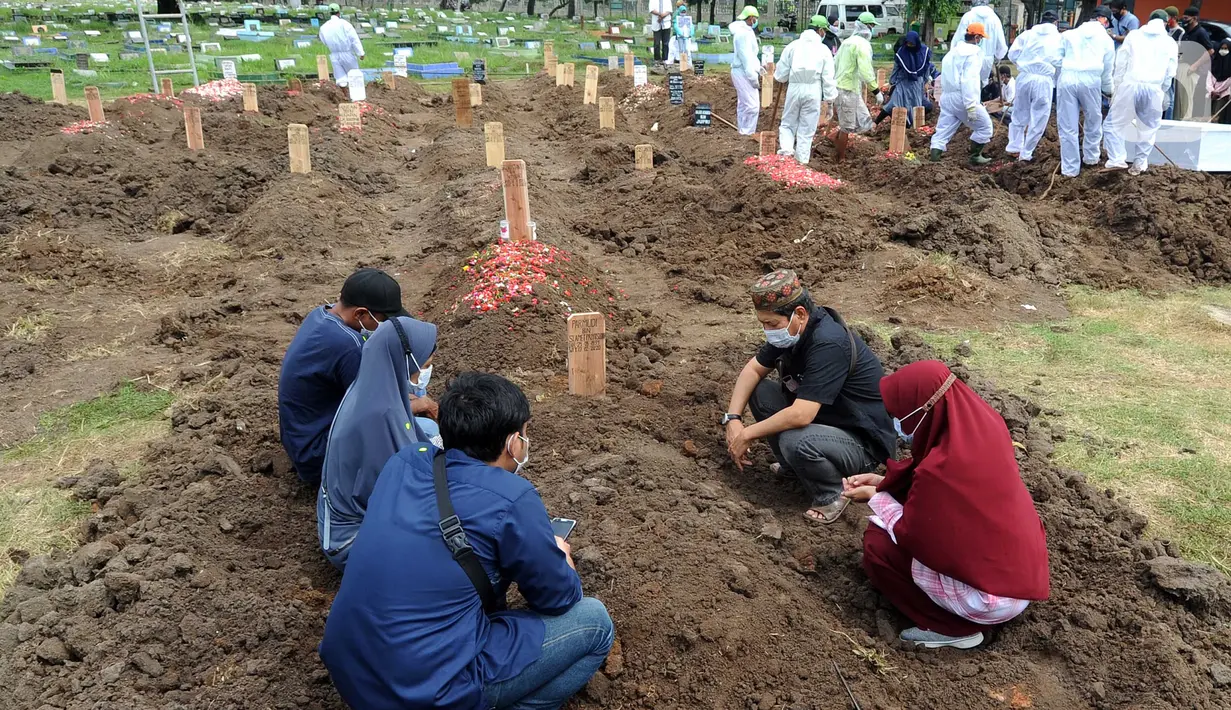 Sebuah keluarga berdoa di salah satu makam khusus Covid-19 di TPU Tegal Alur, Jakarta, Kamis (17/12/2020). Hingga hari ini, intensitas pemakamanan korban covid-19 di DKI masih tinggi dengan rata-rata yang dimakamkan mencapai 30 hingga 38 jenazah per hari. (merdeka.com/Arie basuki)