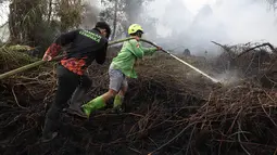 Petugas pemadam kebakaran menyemprotkan air untuk memadamkan api yang melalap lahan gambut di Kubu Raya, Kalimantan Barat, Indonesia, Selasa, 11 Agustus 2026. (Foto AP/Stefanus Taman)