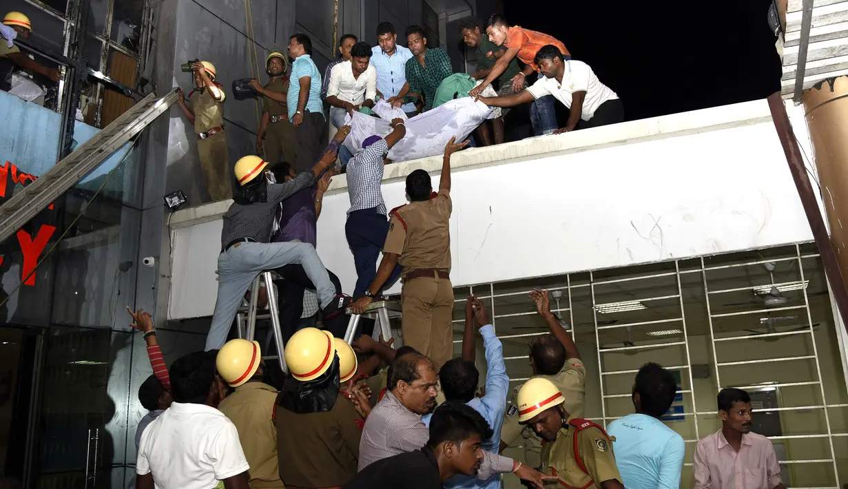 Petugas penyelamat menurunkan tubuh salah satu korban kebakaran besar yang melanda rumah sakit SUM Bhubaneshwar di Odisha, India Timur, Senin (17/10). Api diduga muncul karena hubungan arus pendek, namun dugaan itu masih diselidiki pihak berwenang. (AFP)