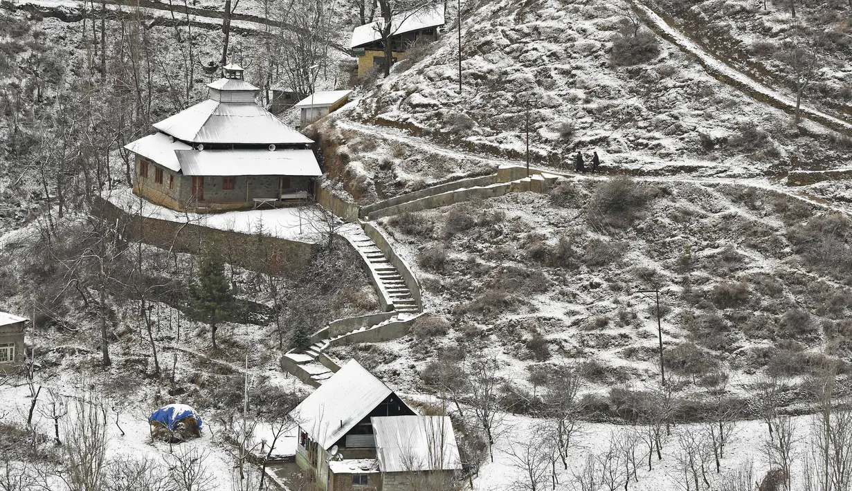 Rumah-rumah yang tertutup salju digambarkan setelah hujan salju di pinggiran Srinagar, Kashmir, India, pada 29 Desember 2020. Hujan salju memutihkan kota utama di Kashmir tersebut. (Photo by Tauseef MUSTAFA / AFP)